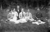 Familjegrupp sju personer i gräset.
Johannes Natanael Bäckman och Edit Bäckman (med slips).