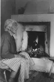 Rumsinteriör, en kvinna vid öppen spis.
Klara Eriksson, Ykullen.
Klara härstammade från finn byn Trösslingstorp (Tiveds sn).