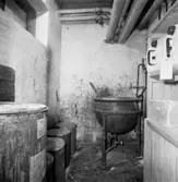 Hattillverkning. 185/67 Tillverkning av apperetur. I en kopparkittel på ben sjudes 100 liter 6-gradig schellacklösning och tappas sedan på gröna träkaggar (t.v. på bilden).