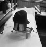Lindbergs Strå- och Filth. Hattillverkning. 225/67 Apparat för hattblockning. Denna är elektrisk. Hatten kan blockas ut till önskad storlek, finnes gradering på foten. Foderbandet pressas här efter isättning.