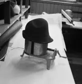 Lindbergs Strå- och Filth. Hattillverkning. 225/67 Apparat för hattblockning. Denna är elektrisk. Hatten kan blockas ut till önskad storlek, finnes gradering på foten. Foderbandet pressas här efter isättning.