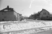 En vinterbild med bostadshus utmed en gata i Huskvarna. Höga snövallar är upplogade utmed gatan.