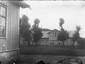 Huset är Vilhelmsberg, där handelsboden låg i vänstra delen. Ägare till affären var Vilhelm Sikén som hade byggt huset 1898. Han hade tidigare haft en affär på Höjder. I vänsterkanten närmast kameran syns skolan.