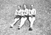 Tre unga män sitter på en gräsmatta med armarna i kors. Från vänster Bror Eriksson, Helmer Garthman och en okänd. Mölndal, 1935.