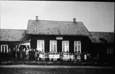Barn och lärare framför folkskolan.