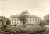 Falköpings första lasarett. Öppnades 15 oktober 1856. Byggnaden flyttades till kv. Byggmästaren, det s.k. Kalvhagen. Helt nytt lasarett invigdes 10 januari 1905. Till vänster tvättstuga m.m. Till höger överläkarbostad.