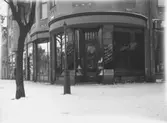 Alfred Jörle, affärsbyggnad, skyltfönster.
(Sybehör, herrekipering; rikhaltig sortering av dam- och herrunderkläder i ylle och bomull; vita vävnader).
Hörnet av Storgatan 26/Järnvägsgatan 14.