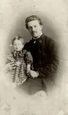En liten flicka och en man.
Löjtnant Falkman och Juliana Fredrika Lovisa Lagerholm (1862 - ). Hon gifte sig med Emil Magnus Ludvig Mannerfeldt.
Hon är dotter till Wilhelmina Lagerholms bror, Per Didrik Lagerholm (1824-1875), kyrkoherde i Södertälje och hans första hustru Juliana Christina Lagerholm, född Åstrand (1827-1864).