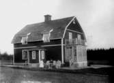 Bostadshus, tre personer framför huset.
Lärare Elanders hem i Rönneshytta, dit han flyttade före 1920.