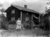 Bostadshus, två personer framför huset.
Alma Holmberg och hennes far.