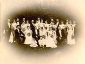 Ett socitetsbröllop i Falköping i slutet av 1800-talet. Brudparet med tärnor och marskalker. Fröken Nanny Janzons bröllop med bankdirektör E.Tegnér, Lindesberg. Tärnan här närmast är fröken Mary Frykberg, sedermera gift med ryssen Subkow, och svärmoder till tyske Kejsar Wilhelms syster.