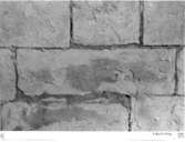 Södra koret. Norra muren. Andra stenen väster om öppningen till mittkoret i andra skiftet från kälskiftet (se foto 22) med i putsen före finslipningen inristade bokstavstecken (R LU).