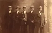 Gruppfoto fyra herrar i mörk kostym och halmhatt, 1 herre ljus kostym och filthatt, längst till höger Carlo Karlsson.