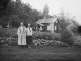 Justina Johansson på Huset och hennes dotter Ida, Krokstads socken i Sörbygden, fotograferade framför stengärdsgård, potatisodlingen och bostaden.