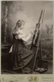 Ett porträtt av Ester Ellqvist-Bauer när hon som 17-åring sitter vid sitt staffli och målar. Bilden blev prisbelönt vid Stockholmsutställningen 1897.