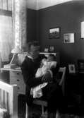 Man med spädbarn i sina armar, hemmiljö, ”1917 C” på asken
	Metallutfällning.