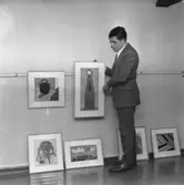 En man hänger tavlor på konstnärsgården i Huskvarna.