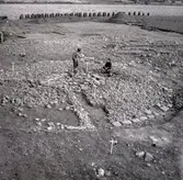 Arkeologisk utgrävning. En stensättning är avtorvad. Kantkedjan och mittpackningen av större stenar syns tydligt.