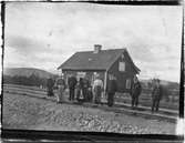 John Bauers Lapplandsresa sommaren 1904. Ett grupporträtt med människor framför ett stationshus. Männen är klädda i uniform.