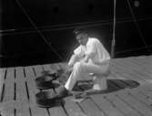 Man som tvättar grytor utanför båt 1917.