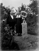 Dam och man poserar i trädgård vid solur ”Åkare Kristersson”
	Metallutfällning, repor.