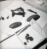 Föremål från utgrävningar vid Hässleby. Bland annat en pincett, sländtrissor och spännen.