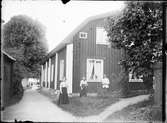 Man och kvinnor utanför bostadshus, nuvarande Guldskärsgatan 2, Östhammar, Uppland