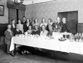Gruppbild vid ett kaffebord. Enligt Walter Olsons journal är bilden beställd av fröken Thua Nyström ifrån Husållsskolan Anita.