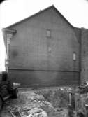 En rivning bredvid kortsidan av ett hus. Enligt Walter Olsons journal är bilden beställd av Skånska cement.
