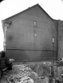 En rivning bredvid kortsidan av ett hus. Enligt Walter Olsons journal är bilden beställd av Skånska cement.