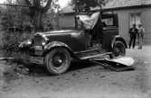 Bagare Lundströms bil. På skylten står M 111 76 bilen är krockad 1932
	Metallutfällning, fingeravtryck, missfärgad lätt rosa.