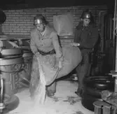 Två brandmänn tömmer innehållet från en säck på golvet.