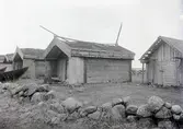 Fiskebodar vid hamnen. Av ek i stolpar. Tak med tång samt flis i foten. Svale med små bänkar av kalkflis.