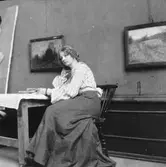 Ester Bauer sitter vid ett bord med böcker framför sig.