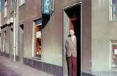 En man står i dörren till Josef Anderssons Porslinsaffär med adress Kvarnbygatan 4 vid Gamla Torget i Mölndal, 1960-1970-tal. I samma hus låg även Rasmussons skoaffär.

För mer information om bilden se under tilläggsinformation.