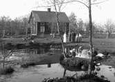 En och en halvvånings bostadshus, familjegrupp fem personer framför huset.
Vahlstedt