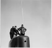 Lennart Wållberg Norrköping var förste kock på ubåten Neptun 1954 Neptuns långresa 1954.
Fartygschefen, Bertil Erkhammar övervakar torpedbärgning från tornet.