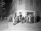 Smärre folksamling utanför konsums butik i hörnet av Drottninggatan–Östra Torggatan år 1931.
