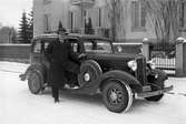 Herre med Chevrolet på en bild från 1934. Bilen kommer troligen från Geijers Motoraffär, agent för GM i Karlstad. Bilden togs på Museigatan som då fortfarande hade kvar sitt gamla namn Älvgatan.
