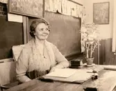 Lärarinnan Agda Carlson vid katedern i Grevedämmets skola i Mölndal, ca 1950.

För mer information om bilden se under tilläggsinformation.