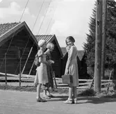 Tre barn utanför träbyggnader.