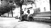 Fyra kvinnor på bänk i stadsmiljö.