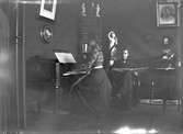 Interiör med kvinna vid piano och läsande man, Hamrånge.