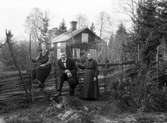 Oskar Andersson med hustru Anna och dottern Ester vid rågärdesgården mellan  nummer 6 och nummer 9. Familjen bodden i gården i bakgrunden som tillhörde Åsmundshyttan nummer 9.