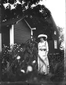 Elna Brundin i Hemlinggrind. Hon poserar framför en lekstuga till vänster.