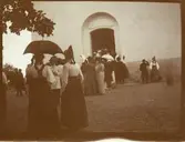Troligtvis entrén till Rättviks kyrka med nationalklädda kvinnor och män.