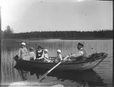 En roddtur, troligtvis på Lingan utanför Lingbo. Elna Brundin med vidbrättad hatt sitter med sina döttrar Karin och Ingrid. Mannen som ror okänd.