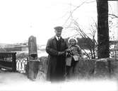 David Brundin på bilutfärd med dottern Eva. Det är vår och hon har vitsippor i famnen. Bilden är tagen vid Karl XIII:s bro över Dalälven vid Älvkarleby.