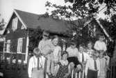 Barnen samlade på Brämen framför skogvaktarbostaden. Familjen har besök av kusiner från Stockholm, Gunnar, Brita och Bertil Malmberg.