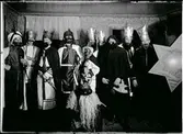 Julspelsgrupp/stjärngång i Köla i Värmland 1928. Figurerna är från höger: stjärnbäraren, en av de vise männen, timmermannen, två vise män, Judas, Svarte kungen, Herodes, dennes tjänare och i förgrunden julbocken.